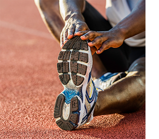 Image of an athlete stretching while sitting on a track made from Treasure Valley Rubber Mulch